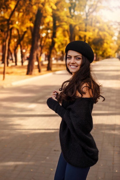 Vrouw met zwarte hoed op de achtergrond van herfstbladeren