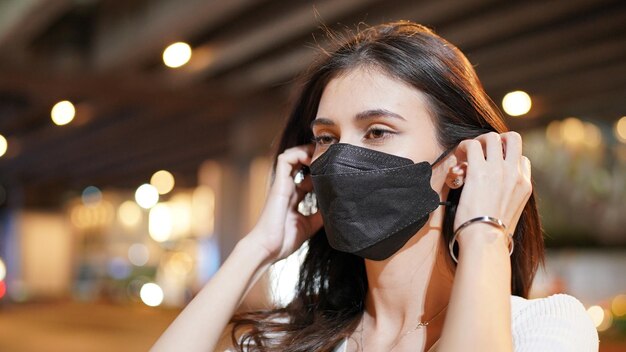 Vrouw met zwarte kleur gezichtsmasker staande op straat.