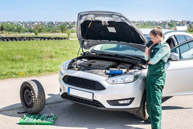 Foto vrouw monteur zoekt problemen met de motor van een auto