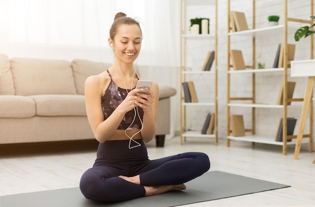 Vrouw na het beoefenen van yoga ontspannen op mat met smartphone