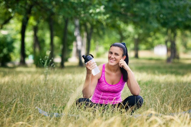 Foto vrouw na yoga zittend op gras glimlachen