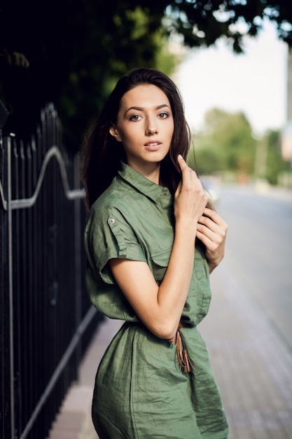 Vrouw naast een hek met een groene jurk