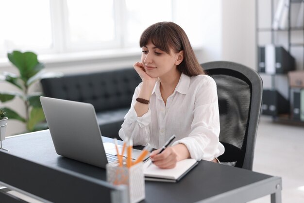 Vrouw neemt aantekeningen tijdens webinar aan tafel binnen