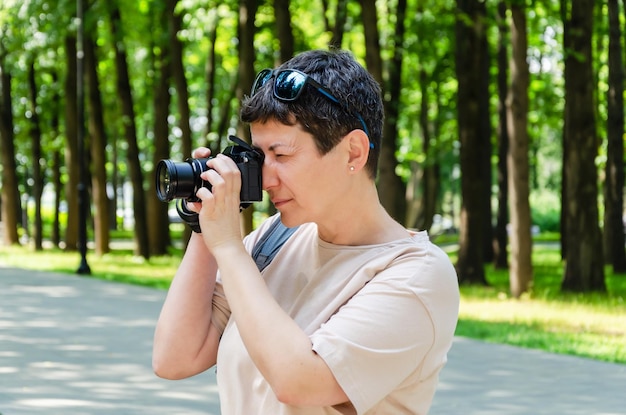 Vrouw neemt foto's met haar camera op een zonnige zomerdag in een stadspark Toeristenfotograaf met zijn camera in het park