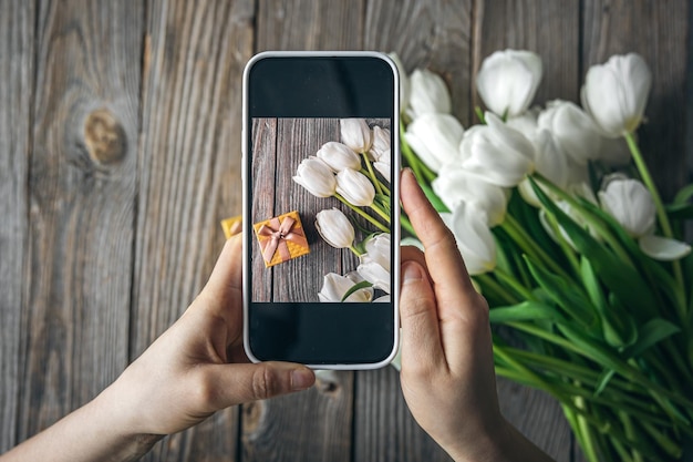 Vrouw neemt foto van een boeket witte tulpen en een geschenkdoos