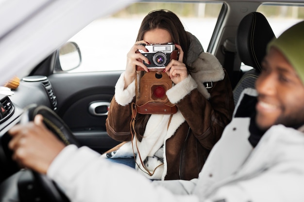 Vrouw neemt foto van man in de auto tijdens een winterse roadtrip samen