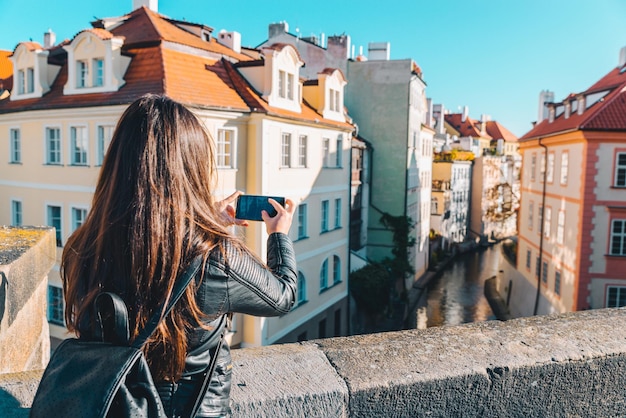 Vrouw neemt foto van rivierkanaal tussen gebouwen op haar telefoon