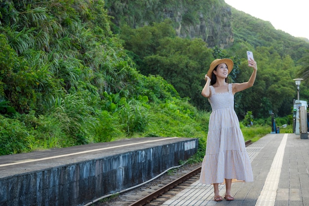 Vrouw neemt selfie op mobiele telefoon op het treinstation