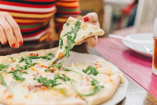 Vrouw neemt stuk pizza close-up soft focus