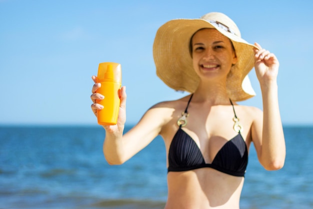 Vrouw neemt zonnebrandcrème op zeeachtergrond Lachende vrouw met zonnebrandcrème