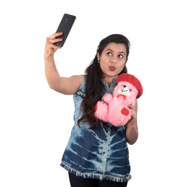 Vrouw nemen foto of selfie met mobiele telefoon en teddybeer te houden