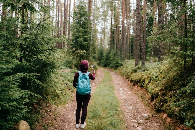 Vrouw nemen foto van boslandschap met smartphone in haar hand