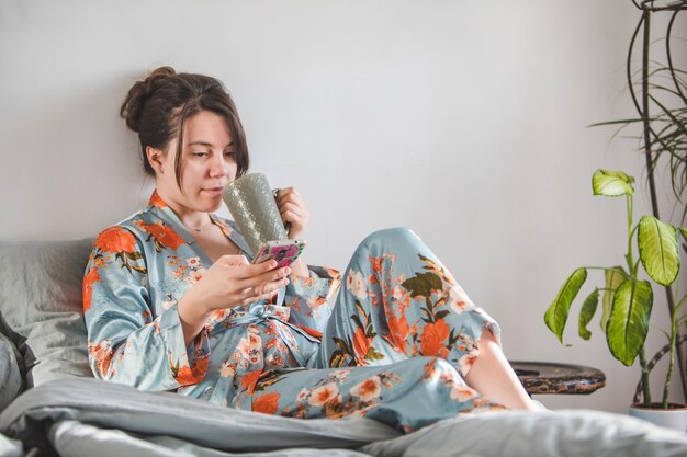 Vrouw ochtend in bed met telefoon internet surfen