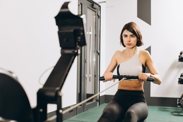 Vrouw oefenen op roeimachine onderdeel van circuit training warming-up cardiosessie