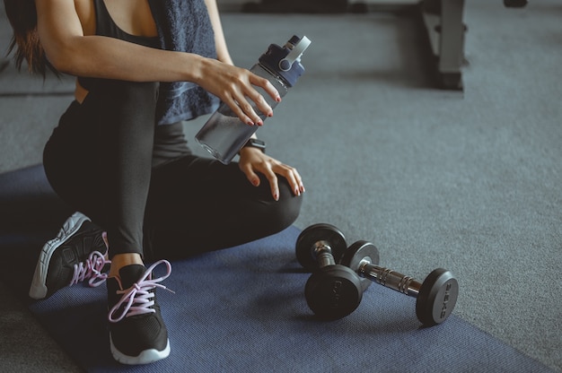 Vrouw oefenen training in sportschool fitness breken ontspannen na het trainen van sport met halter