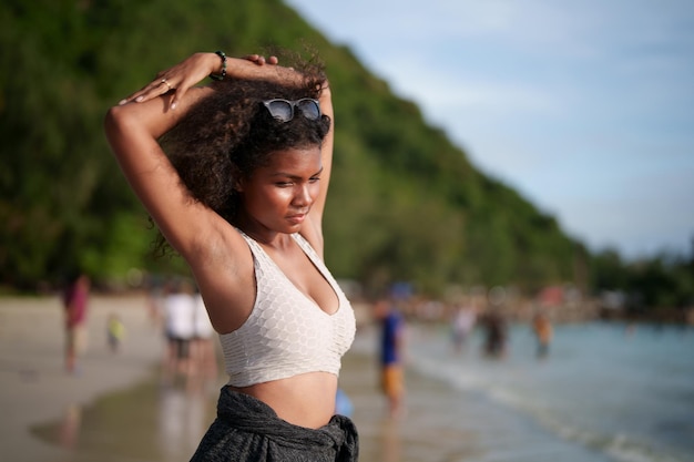 Vrouw oefent en rekt spieren uit voor buitentraining portret sexy aziatische afrikaanse dame die zich voorbereidt op fitness op het strand