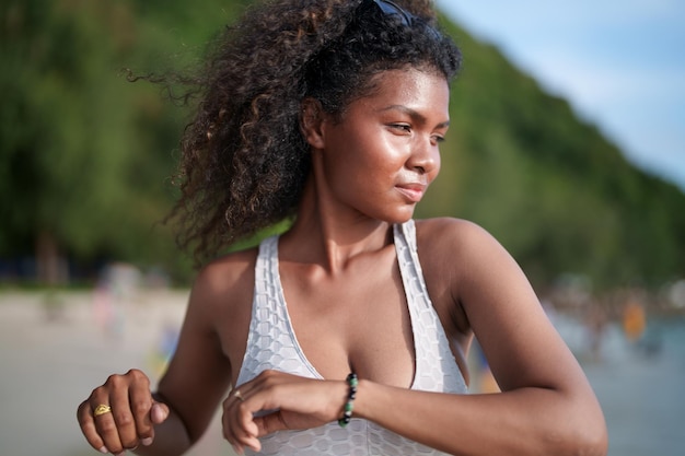 Vrouw oefent en rekt spieren uit voor buitentraining Portret sexy Aziatische Afrikaanse dame die zich voorbereidt op fitness op het strand