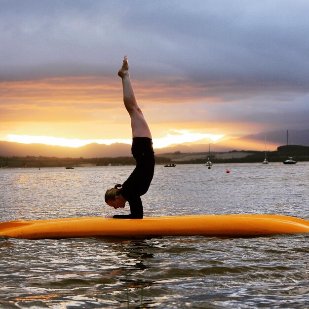 Foto vrouw oefent op paddleboard tijdens zonsondergang