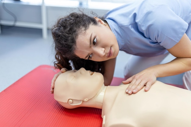 Vrouw oefent reanimatie-techniek op dummy tijdens EHBO-training EHBO-training Cardiopulmonale reanimatie EHBO-cursus op reanimatie-dummy