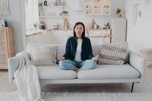 Vrouw oefent yoga ontspannen ademen zittend op de bank thuis gezonde levensstijl stressverlichting