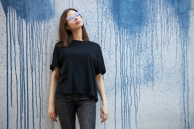 Vrouw of meisje met een zwart blanco katoenen t-shirt met ruimte voor uw logo, mock-up of ontwerp in een casual stedelijke stijl