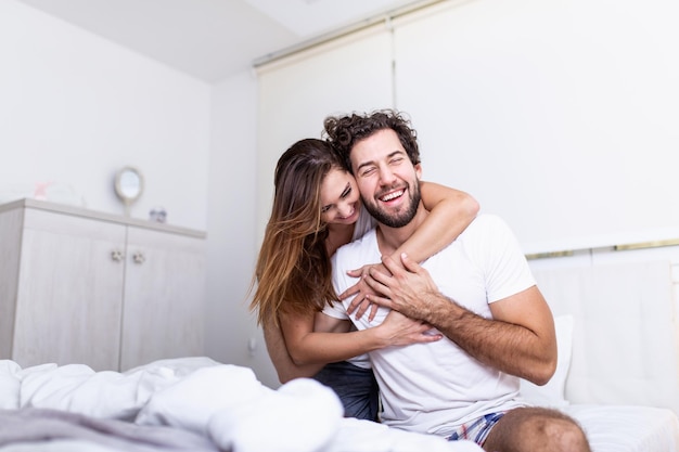 Vrouw omhelst haar partner in bed, gelukkig paar in bed met emoties en liefde. Mooie verliefde paar zoenen in bed. mooie jonge paar samen op het bed liggen.