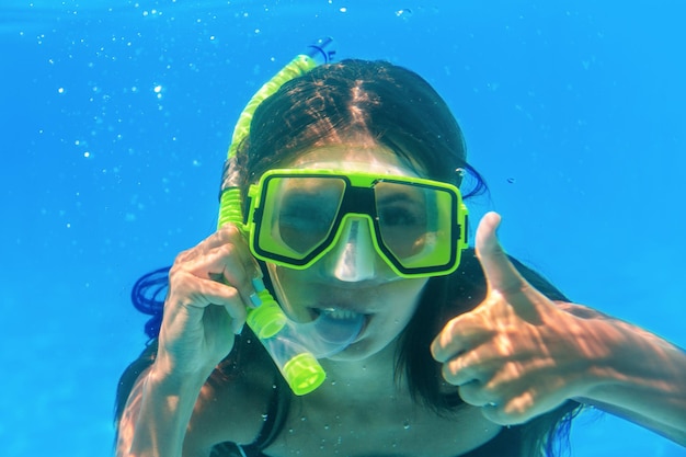 Vrouw onder water in masker met duim omhoog