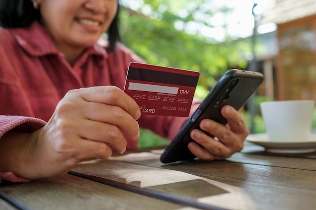 Vrouw online winkelen met creditcard bij coffeeshop in outdoor.close-up hand met smartphone