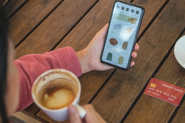 Vrouw online winkelen met creditcard bij coffeeshop in outdoor.close-up hand met smartphone