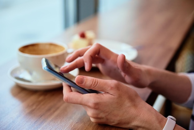 Vrouw ontbijten in café, smartphone gebruiken in café