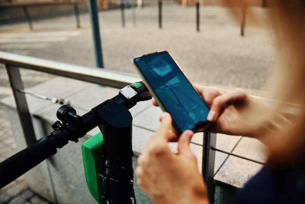 Foto vrouw ontgrendelt elektrische scooter te huur met een smartphone-applicatie