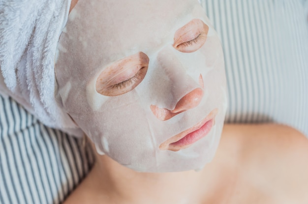 Vrouw ontspannen in bed met een gezichtsmasker