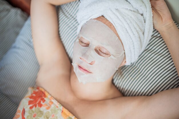 vrouw ontspannen in bed met een gezichtsmasker