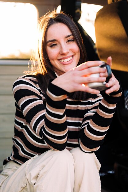 Vrouw ontspannen in een camper met een warm drankje