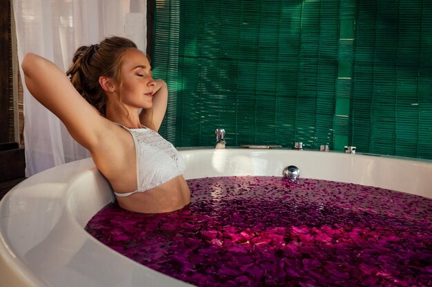 Vrouw ontspannen in rond buitenbad met tropische bloemen biologische huidverzorging luxe spa hotel valentijnsdag alleen huwelijksreis