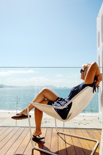 Vrouw ontspannen op het balkon met uitzicht op de oceaan