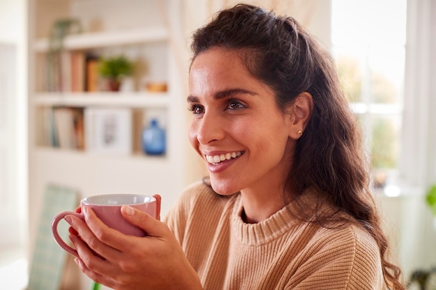 Vrouw ontspannen thuis zittend aan tafel met warme drank