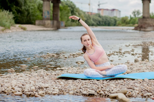 vrouw ontspannen tijdens het mediteren en doen yoga oefening aan de oever van de rivier