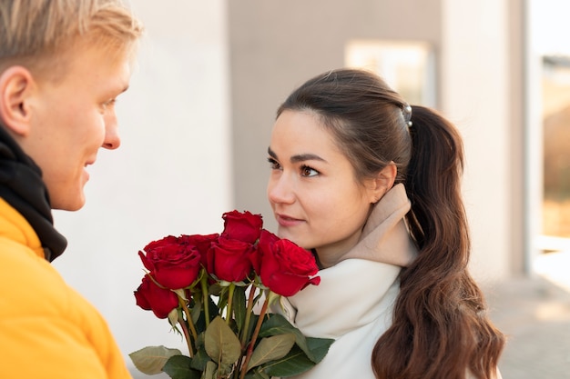 Vrouw ontvangt een boeket rode rozen van vriendje op valentijnsdag terwijl ze buiten is