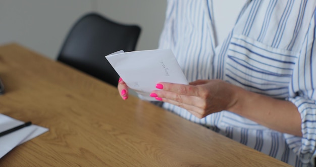 Vrouw ontving een brief met een groetenkaart Closeup vrouwelijke handen trekken groetenkaart uit de envelop