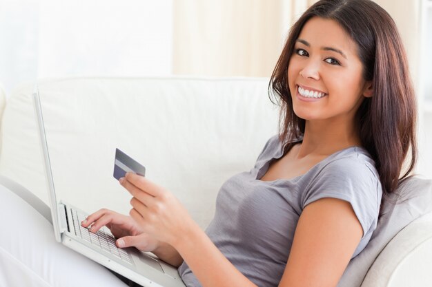 vrouw op bank woriking met laptop glimlachend in de camera