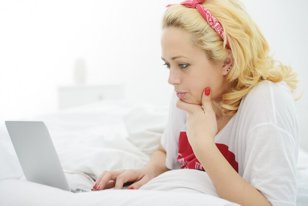 Vrouw op bed in de slaapkamer met een notebook