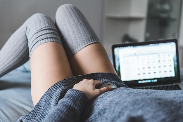 Vrouw op bed met laptop en smartphone in handen. levensstijl concept