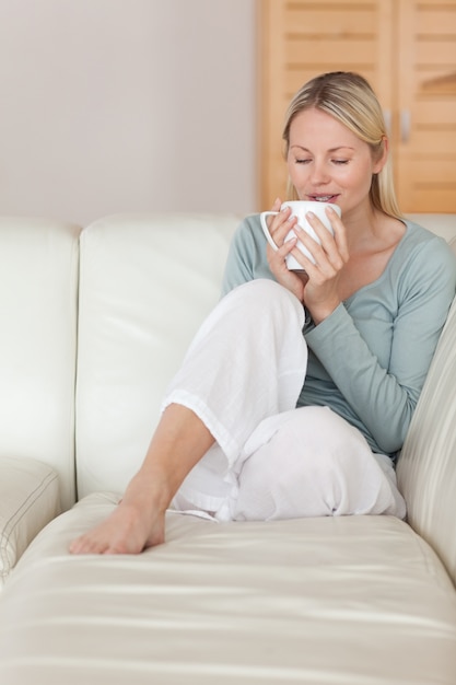 Vrouw op de bank die een slokje koffie neemt