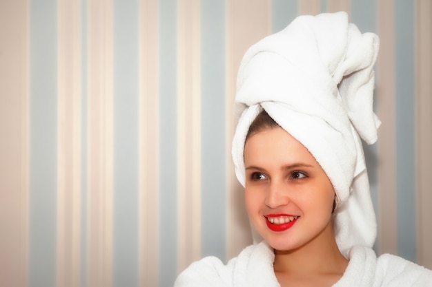 Vrouw op de bank van de hotelkamer na het douchen. Mooie vrouw van Slavische verschijning in kamerjas en handdoek op haar hoofd. Gelukkige dame. Tijd doorbrengen op vakantie. Leuk meisje na gewassen en toont emoties