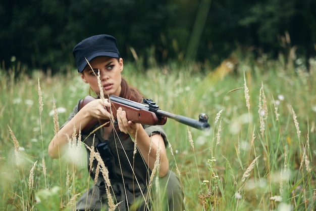 Foto vrouw op de buitenlucht jacht zit op het gras groene bladeren bos achtergrond