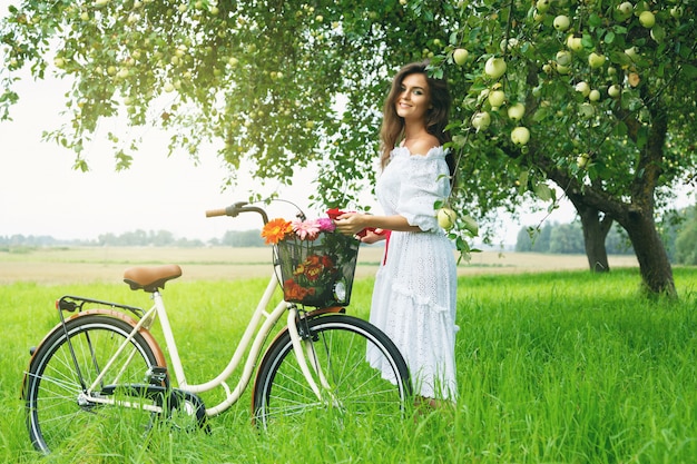 Vrouw op de fiets plukt verse appels uit de boom in de dorpstuin