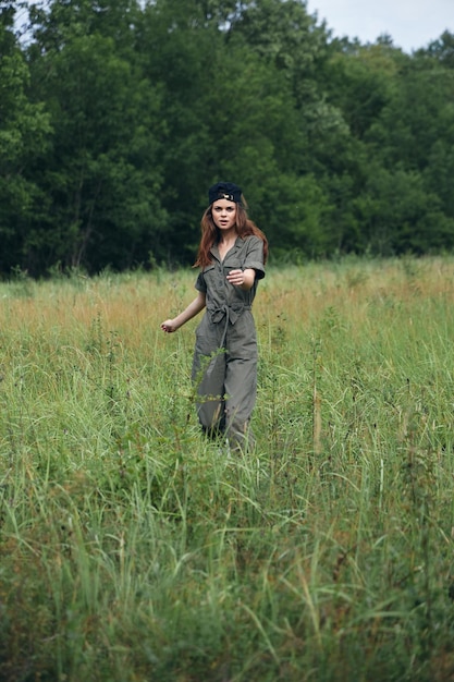 Vrouw op de natuur In een groene jumpsuit hoog gras lopen