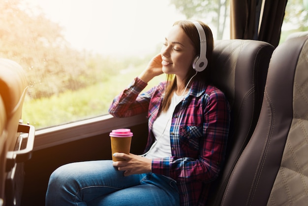 Vrouw op de passagiersstoel van de bus luistert naar muziek