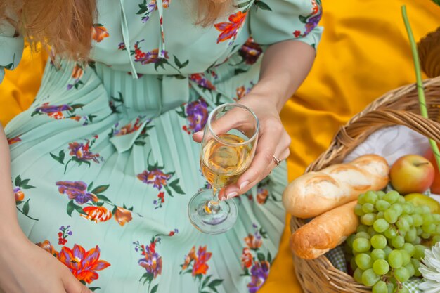 Vrouw op de picknick zit op de gele dekking en houdt wijnglas.